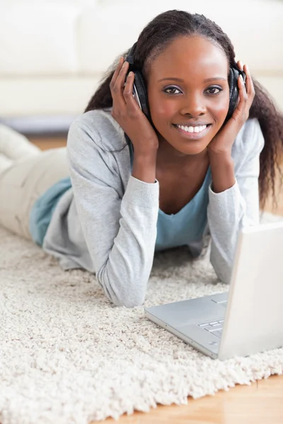 Close up di donna sdraiata sul pavimento con il suo computer portatile ascoltando t — Foto Stock