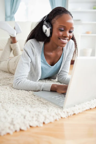 Close up of woman lying on floor with her laptop enjoying music — Stock Photo, Image