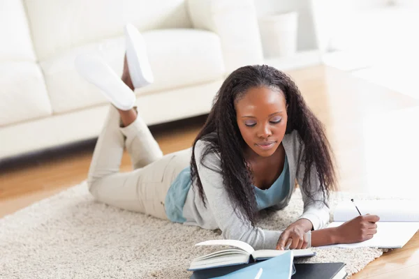 Femme couchée sur le tapis faisant une critique de livre — Photo