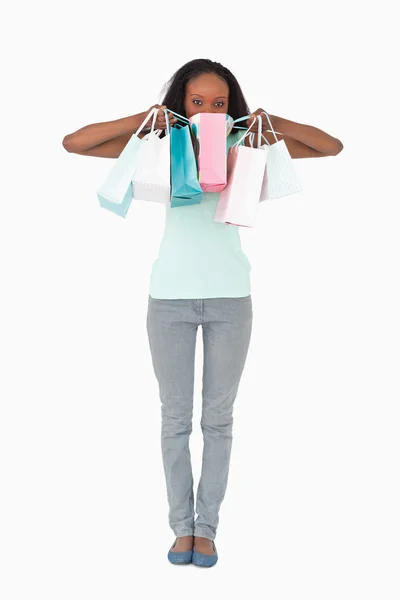 Mulher se escondendo atrás de suas compras no fundo branco — Fotografia de Stock