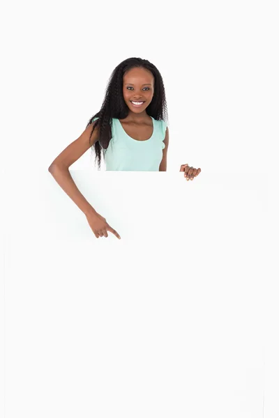 Woman pointing on placeholder below her on white background — Stock Photo, Image