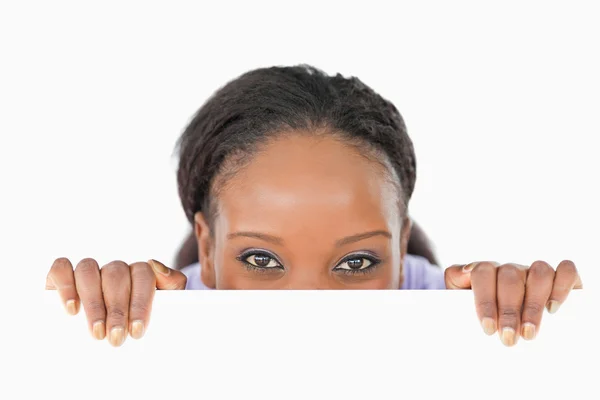Woman taking a look above an edge on white background — Stock Photo, Image