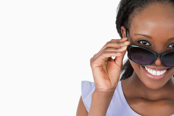 Закрытие женщины, смотрящей на свои солнцезащитные очки на белом бэкграунде — стоковое фото