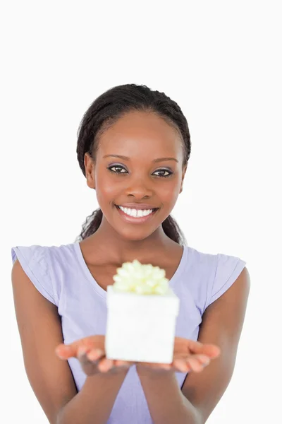 Κοντινό πλάνο χαμογελαστό γυναίκα, κρατώντας ένα δώρο εναντίον έναs άσπρο πλάτη — Φωτογραφία Αρχείου