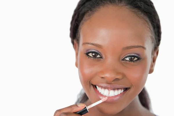 Close up de mulher aplicando brilho labial contra um fundo branco — Fotografia de Stock