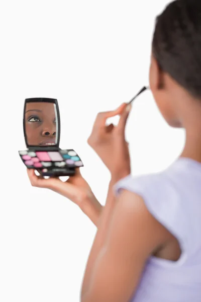 Närbild på skuggning kvinna samtidigt som make-up mot en whi — Stockfoto