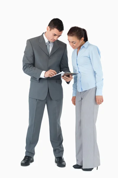 Geschäftspartner beim Blick auf ein Klemmbrett vor weißem Hintergrund — Stockfoto