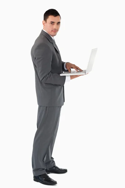 Hombre de negocios seguro con portátil contra un fondo blanco — Foto de Stock