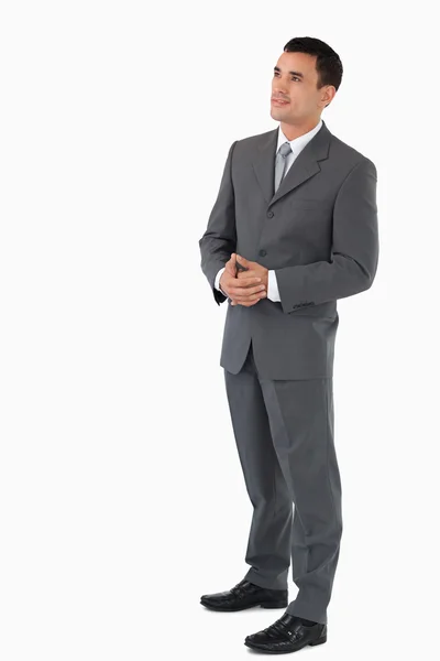 Businessman with hands folded looking upwards against a white ba — Stock Photo, Image