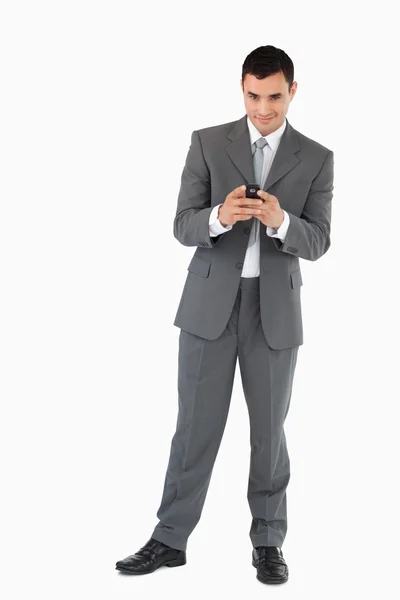 Empresário segurando seu celular contra um fundo branco — Fotografia de Stock