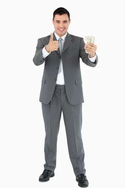 Бизнесмен с банкнотами, показывающий большой палец — стоковое фото