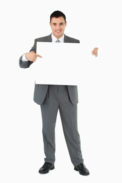 Geschäftsmann zeigt auf Schild, das er in der Hand hält — Stockfoto