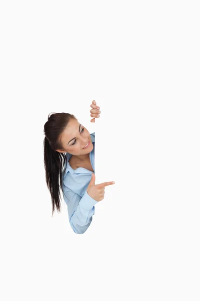 Businesswoman pointing while looking around the corner — Stock Photo, Image