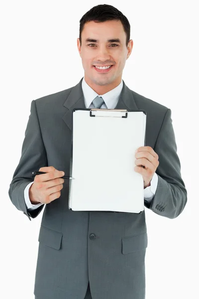 Biznesmen uśmiechający się wskazujący z piórem w schowku — Zdjęcie stockowe