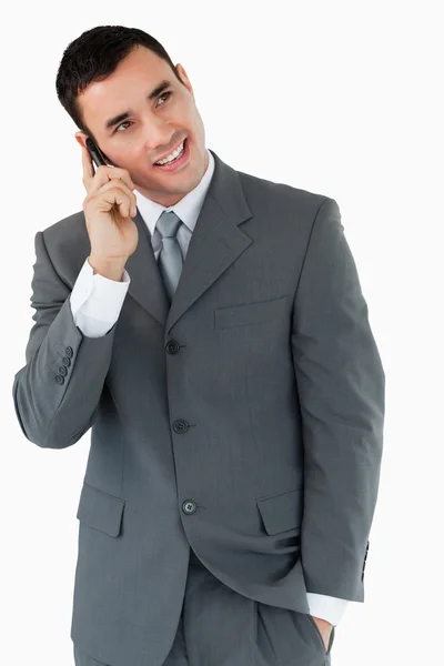 Улыбающийся бизнесмен смотрит по диагонали вверх, пока на телефоне — стоковое фото