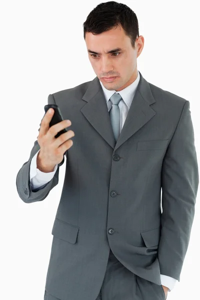 Uomo d'affari dall'aspetto serio che guarda il suo cellulare — Foto Stock