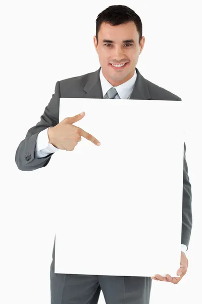 Lächelnder Geschäftsmann zeigt auf das Schild in seinen Händen — Stockfoto