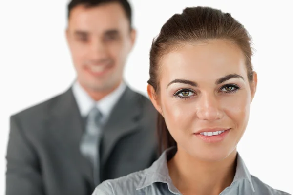 Nahaufnahme einer lächelnden Geschäftsfrau mit einem Kollegen hinter ihr — Stockfoto