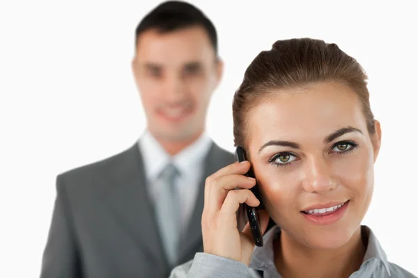 Nahaufnahme einer Geschäftsfrau am Telefon mit einem Kollegen hinter ihr — Stockfoto