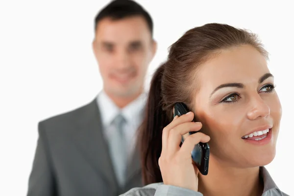 Close up of young businesswoman on the phone with colleague behi — Stock Photo, Image