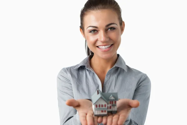Женщина-агент по недвижимости держит в руках миниатюрный дом — стоковое фото