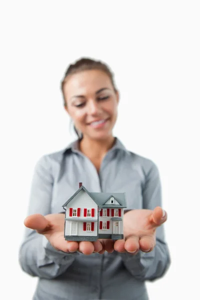 Miniaturowe dom jest w posiadaniu uśmiechający się kobiece agent nieruchomości — Zdjęcie stockowe