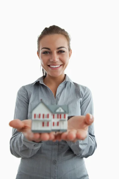 Jovem agente imobiliário feminino apresentando casa em miniatura — Fotografia de Stock