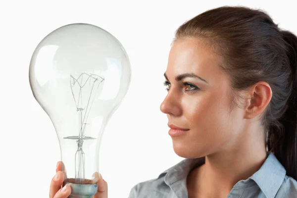 Empresária olhando para a lâmpada enorme em sua mão — Fotografia de Stock