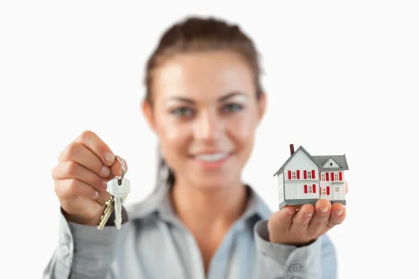 Klucze i domu miniaturze przedstawionych przez kobiece agent nieruchomości — Zdjęcie stockowe