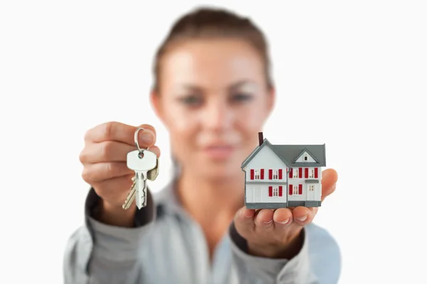 Miniatuur huis en sleutels wordt gepresenteerd door vrouwelijke onroerende goederenagent — Stockfoto