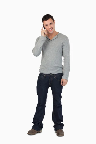 Jovem do sexo masculino de pé, enquanto no telefone — Fotografia de Stock