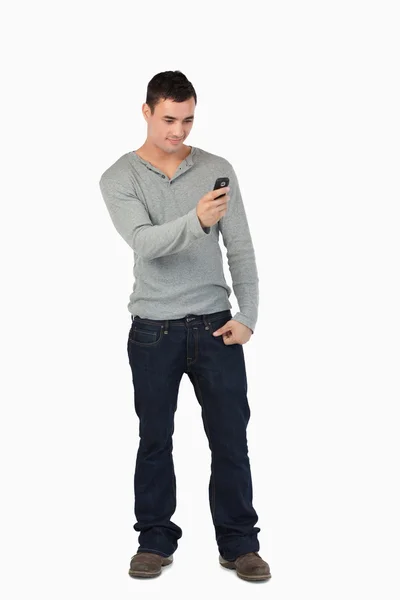 Молодой мужчина стоит и читает текстовые сообщения — стоковое фото