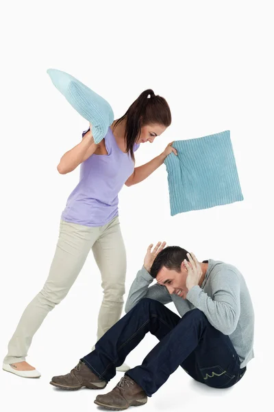 Young female hitting her boyfriend with pillows — Stock Photo, Image