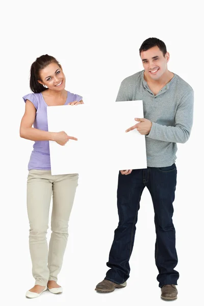 Smiling young couple holding sign together — Stock Photo, Image