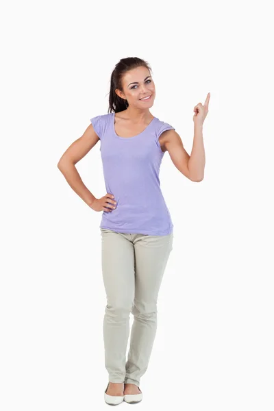 Young female pointing upwards and smiling — Stock Photo, Image