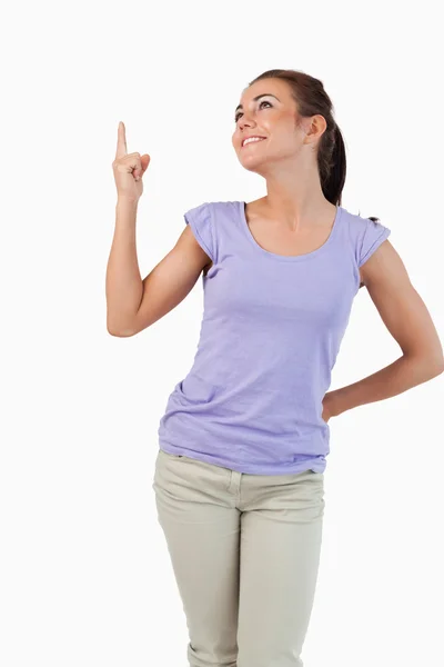Unga kvinnliga ler och pekar uppåt — Stockfoto