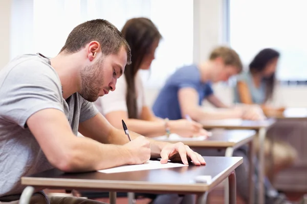 Handsome student writing an assignment — Stock Photo, Image