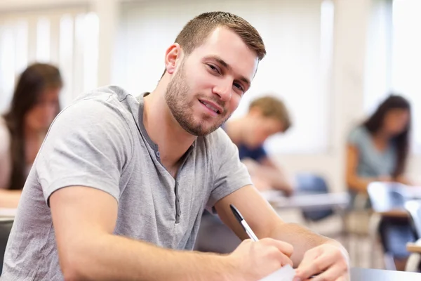 Smiling young adult writing Stock Photo