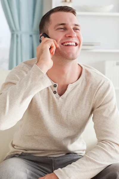 Portrait of a laughing man making a phone call while sitting on Stock Photo