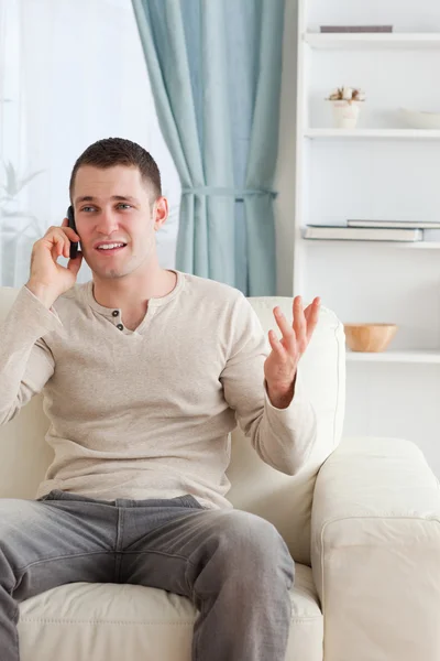 Πορτραίτο ενός άνδρα που μιλάει μέσα από το τηλέφωνο, ενώ κάθεται σε ένα c Royalty Free Εικόνες Αρχείου