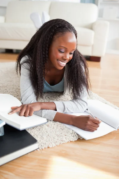 Young woman lying on the floor doing her homework Stock Picture