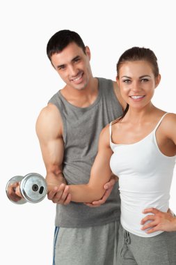 Portrait of a smiling man helping a woman to work out clipart