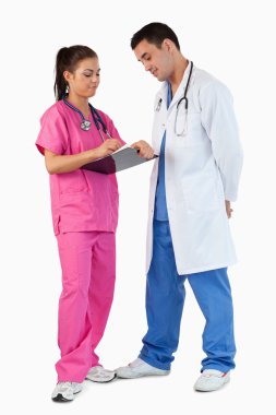 Portrait of a doctor talking while his intern is taking notes clipart