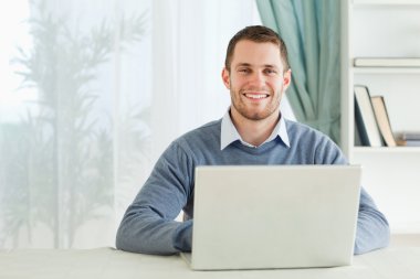 Smiling young businessman working in his homeoffice clipart