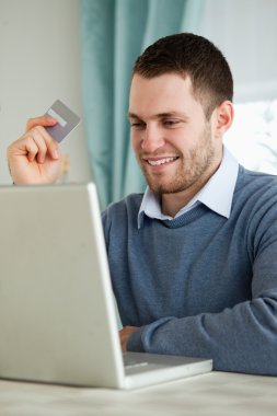 Man with his credit card on his laptop clipart