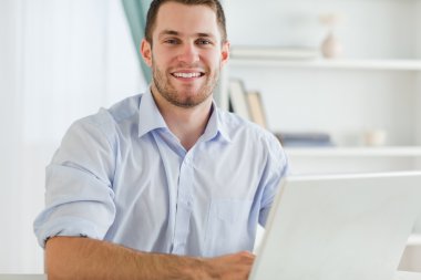 Smiling businessman with rolled up sleeves in his homebusiness clipart