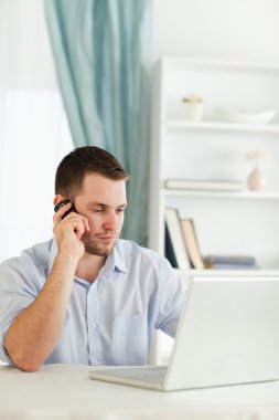 Businessman with rolled up sleeves on the phone in his homeoffic clipart