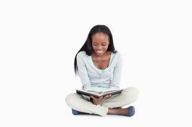 Young woman sitting on the floor reading a book clipart