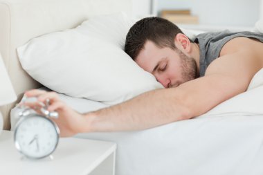 Sleeping man being awakened by an alarm clock clipart