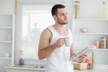 Dreaming man drinking tea while reading the news clipart